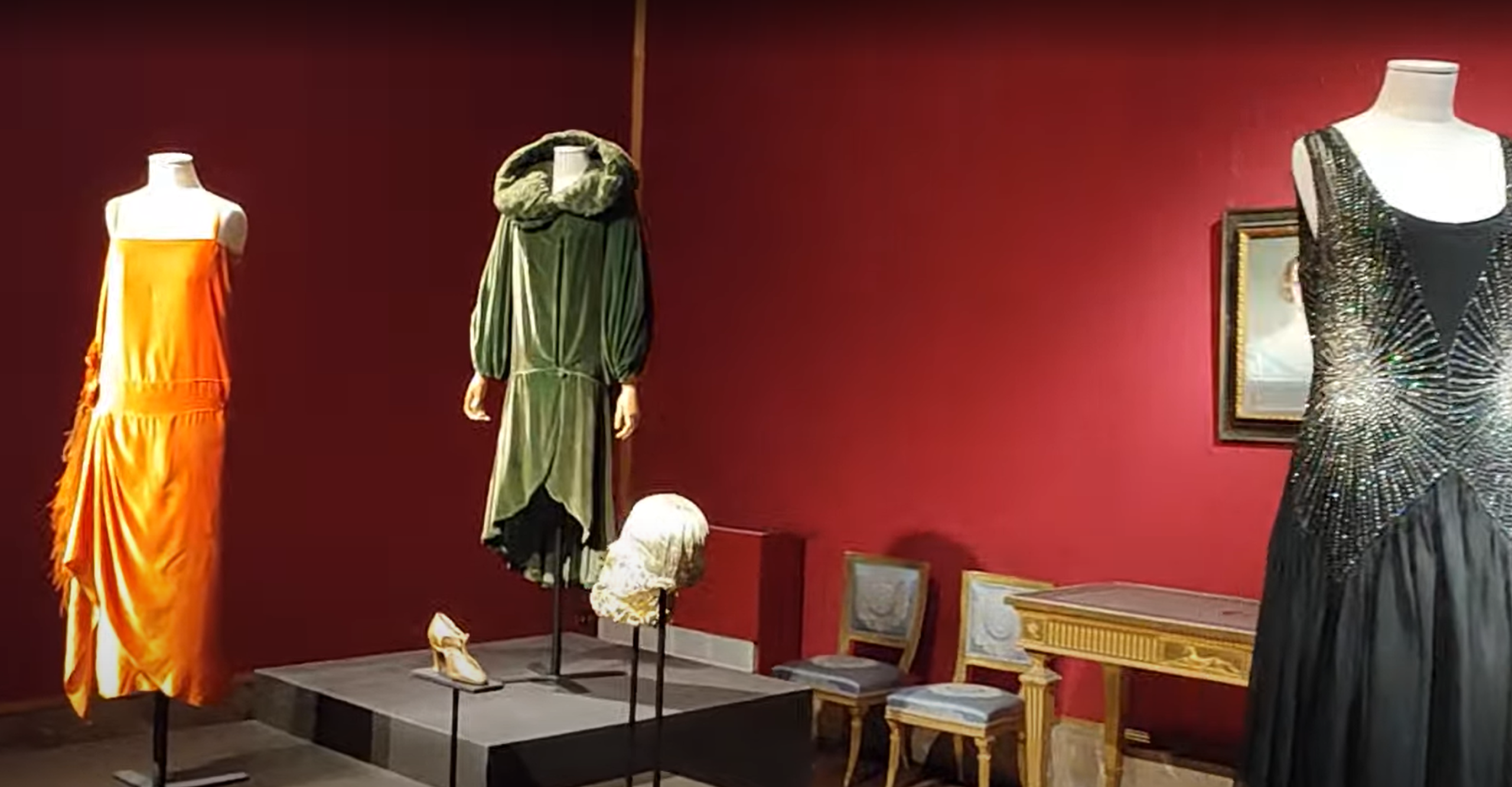 Rotating early 20th-century dresses on display in a red-walled gallery at the Museum of Costume and Fashion, Palazzo Pitti
