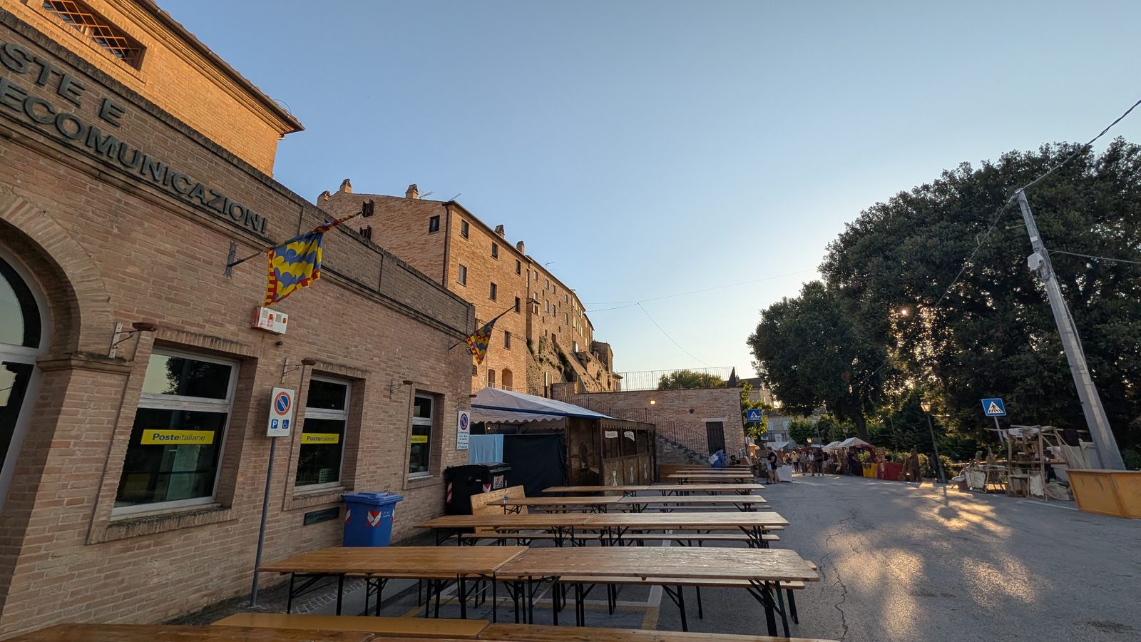Festival tables and Este banners along a street below the walled center of Grottazzolina, Le Marche