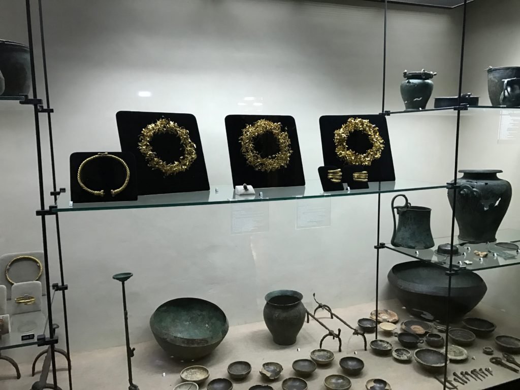 Display case with gold crowns, a torque, and bronze vessels from Montefortino di Arcevia