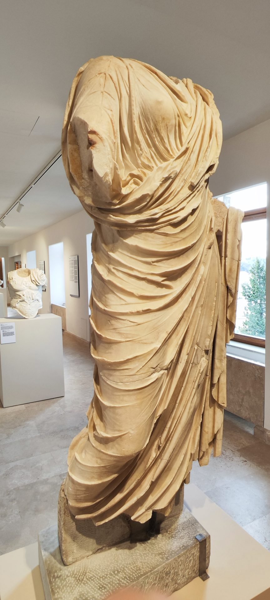 Headless draped marble statue in the Roman galleries of the Ancona archaeological museum