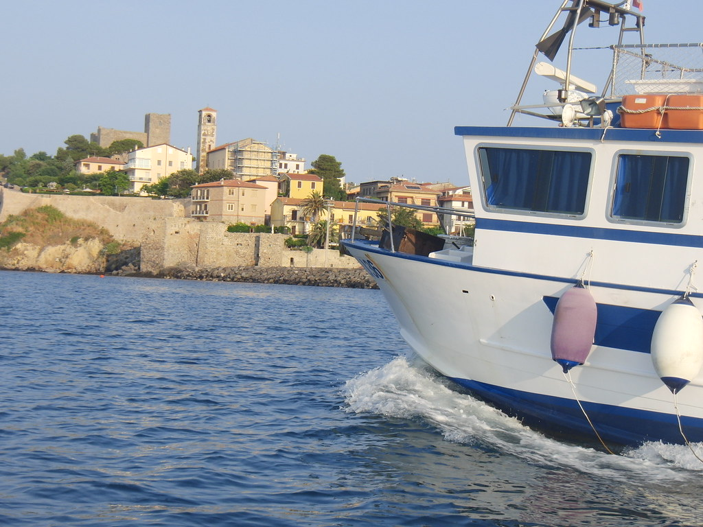 Fishing boat approaching a walled old town on a cliff above the Adriatic Sea