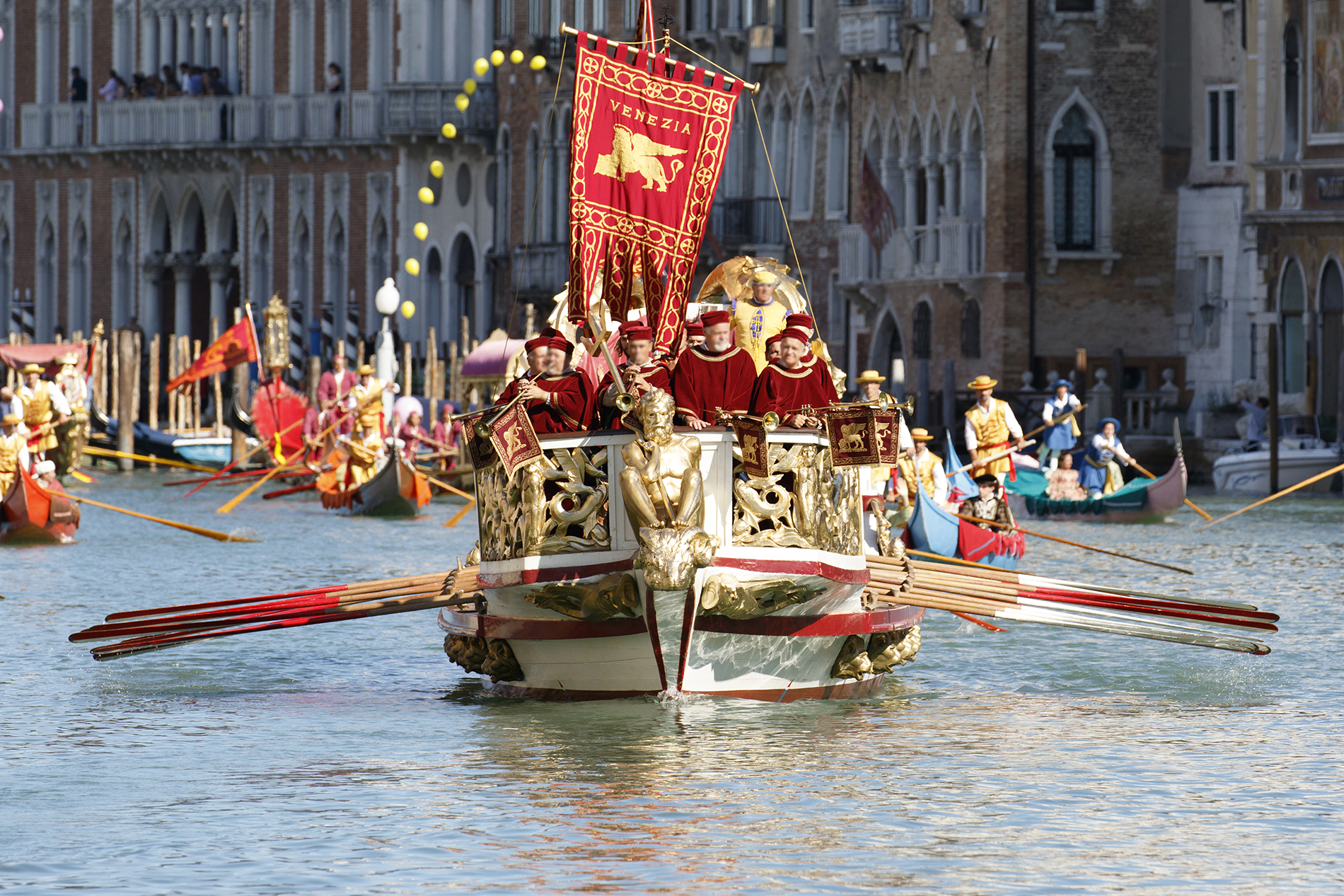 Costumed rowers aboard a ceremonial Venetian boat flying a Venezia banner during the Regata Storica historical procession