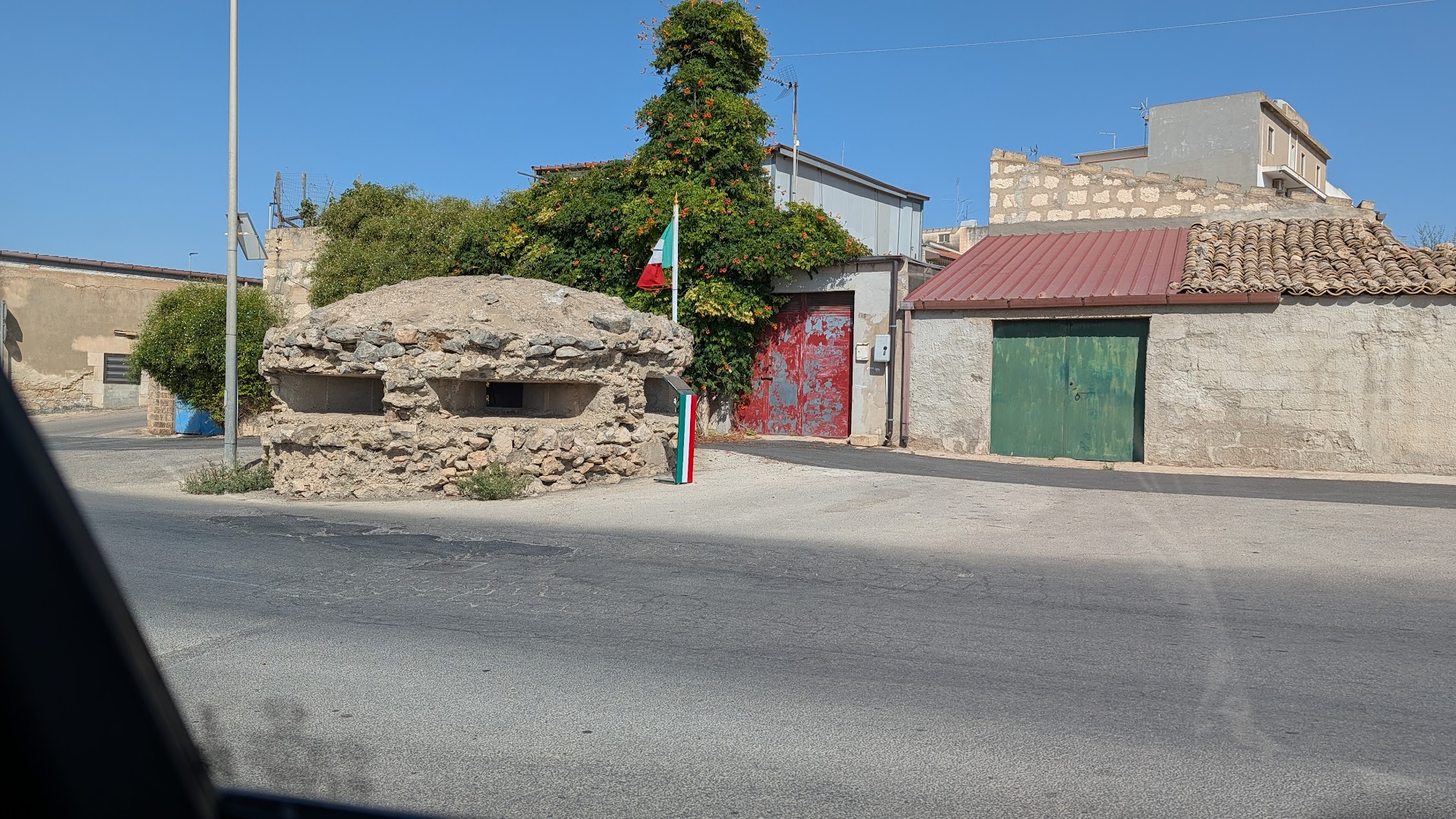 WWII coastal bunker sitting at a street corner in Santa Croce Camerina, Sicily, next to ordinary village houses