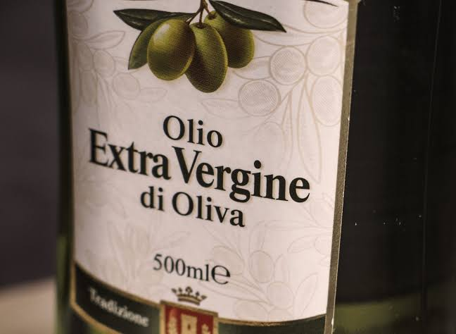 Close-up of an Italian extra virgin olive oil bottle label, showing the legal category and a 500 ml volume declaration.